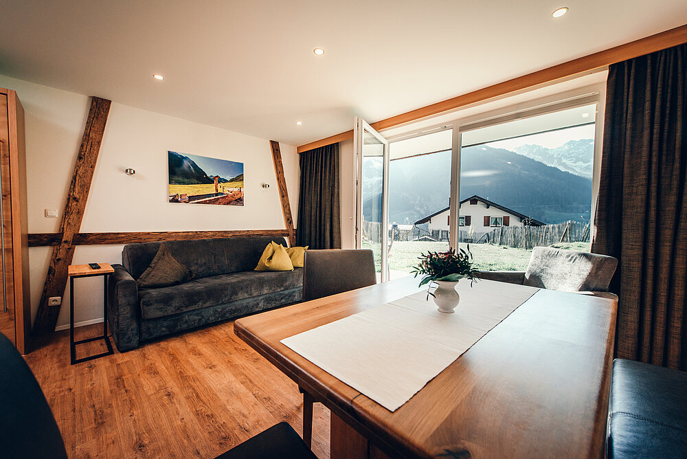 3-kamerappartement type 23a - Hoekbank en eettafel in de woonkamer met panoramisch uitzicht - Almajur Vakantiehotel Mittelberg Kleinwalsertal